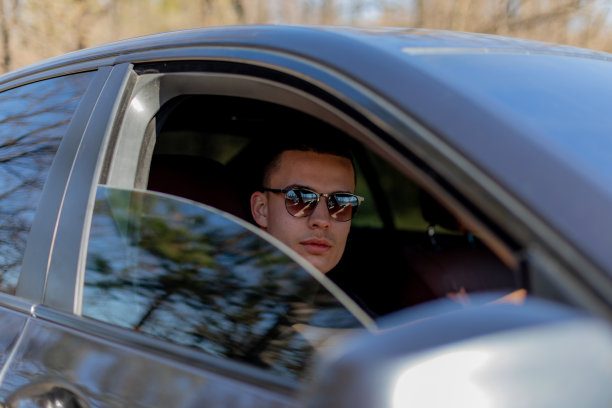 一个年轻人开着车，打电话，在一个阳光明媚的日子里，去自驾游。图片下载