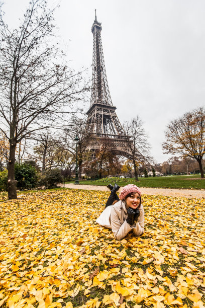 春天的巴黎，一名年轻女子在埃菲尔铁塔前摆姿势图片下载