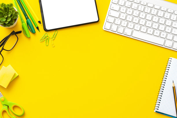 黄色工作区:键盘，数码平板电脑和办公用品与复印空间。图片下载