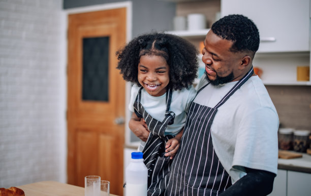 父女在厨房，欢笑，欢呼牛奶比赛，创造珍贵的回忆。图片下载