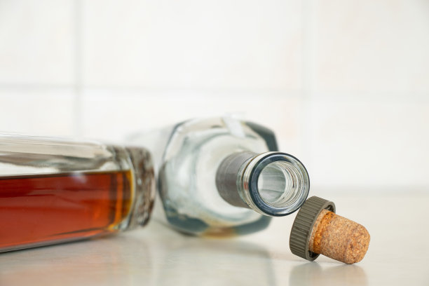 两个瓶子，一个满的，一个空的，里面有干邑酒厨房桌子上的软木塞，家里桌子上有酒，干邑图片下载