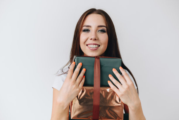 一个精力充沛的女孩庆祝一个有趣的节日的照片。在一个孤立的白色背景上拥抱了很多礼品盒图片下载