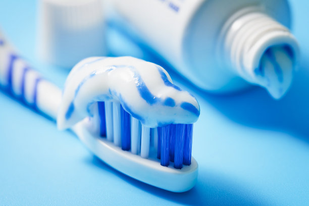 牙刷的特写，涂上牙膏和一管牙膏，背景是白色的。没有人。微距摄影。图片下载