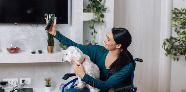 坐在轮椅上的年轻女子和她的狗拍了一张迷人的自拍照图片下载