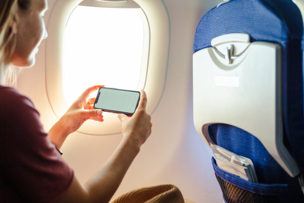 年轻女子在客机上使用智能手机图片下载
