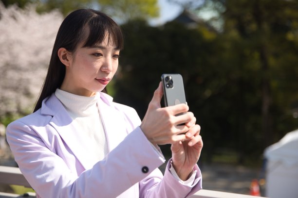 一名日本女子在樱花背后用智能手机拍摄的肖像图片下载