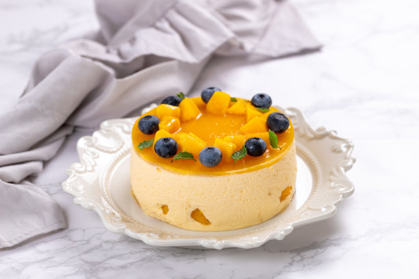 自制芒果芝士蛋糕，配上成熟的芒果和蓝莓图片下载