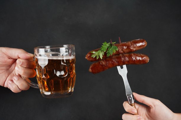 叉子上的烤香肠和泡沫啤酒杯，适合在慕尼黑啤酒节享用图片下载