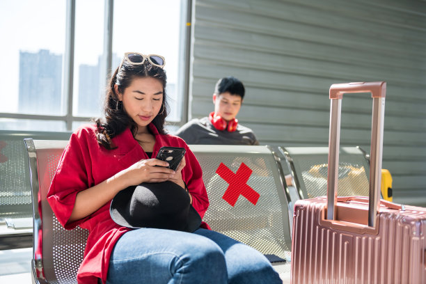 一名亚洲女子在机场候机座位上玩手机图片下载