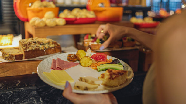年轻女子拿着盘子里的早餐，斋月的开斋时间，开斋时的食物服务，妇女从餐馆的自助餐中取出食物，把食物放在她的盘子里图片下载