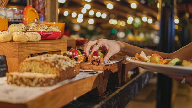 年轻女子拿着盘子里的早餐，斋月的开斋时间，开斋时的食物服务，妇女从餐馆的自助餐中取出食物，把食物放在她的盘子里图片下载