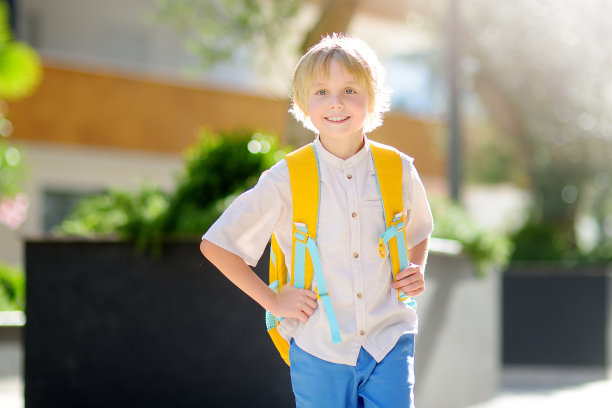 小男生放假后兴高采烈地去上学。孩子在学校的院子里。儿童素质教育。孩子们回到学校图片下载