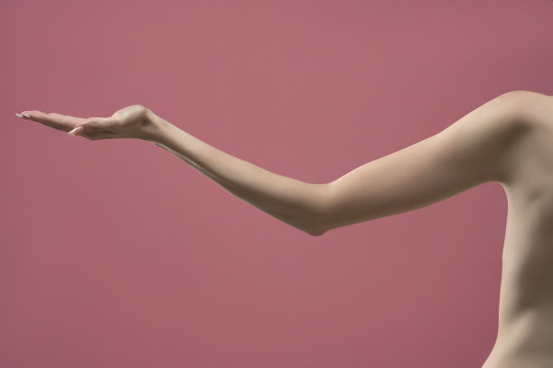 年轻女子伸出瘦削的手臂，张开的手掌拿着想象中的产品。粉红色背景隔离图片下载