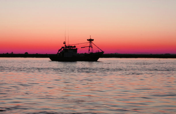 黄昏时离开港口的渔船图片下载