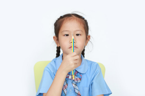 有趣的面孔亚洲小女生拿着和看着铅笔在她的手在白色背景的焦点在孩子的脸。一边学习一边思考的小女孩。图片下载