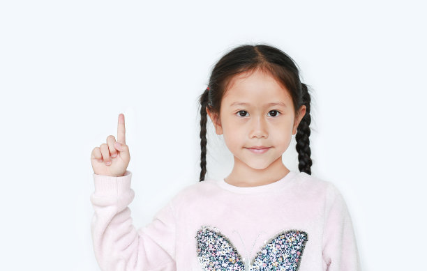 可爱的小女孩指着食指，在白色的背景上呈现出孤立的东西。教育观念中的亚洲女学生。图片下载