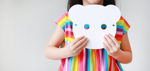 特写小女孩抱着空白的白色动物纸面具在她的胸部在白色的背景。孩子装扮成动物脸的想法和概念。图片下载