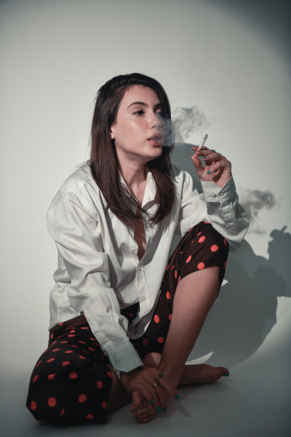 在阴暗的白色背景上抽烟休息的女性图片下载