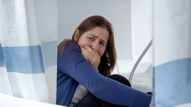 害怕女人成为家庭暴力的受害者躲在浴室里躲避丈夫。家庭暴力受害者的概念，压力，家里的危险，恐惧图片下载