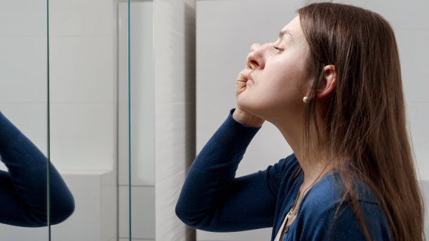 年轻女子在浴室里对着镜子涂睫毛膏的照片图片下载