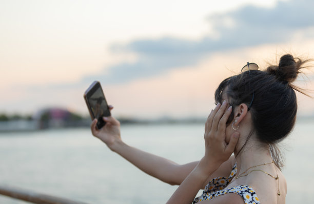 年轻女士正在日落时自拍。图片下载