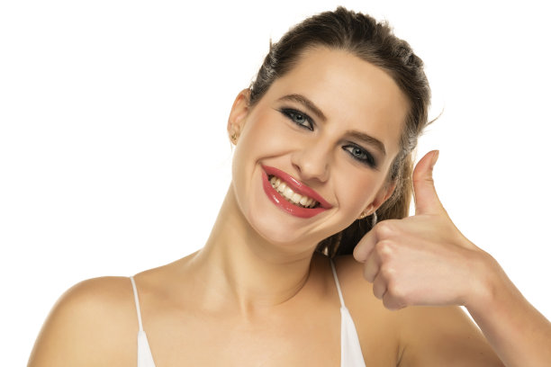 美丽快乐的女人，化着妆，扎着头发，在白色背景上竖起大拇指图片下载