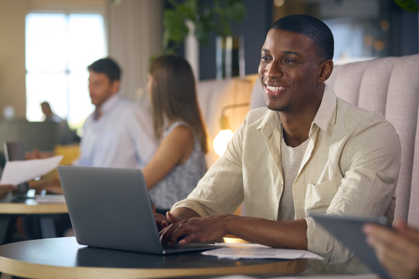 商人在现代办公室的非正式休息区用手提电脑工作图片下载