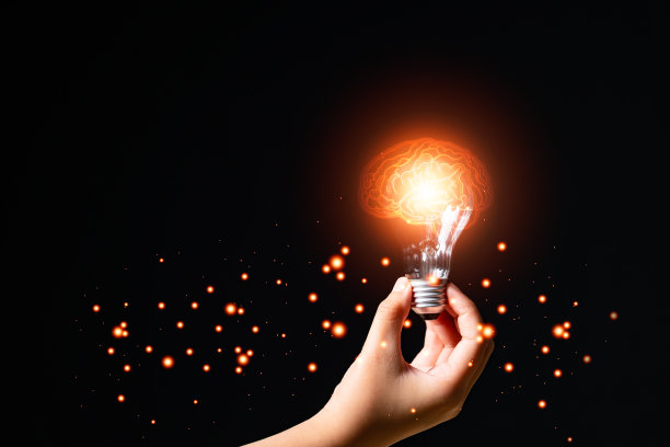 商人手里拿着发光的灯泡在电脑笔记本上的商业图标，笔记本，经营理念，战略，创新，创造，想象和灵感的概念，复制空间。图片下载