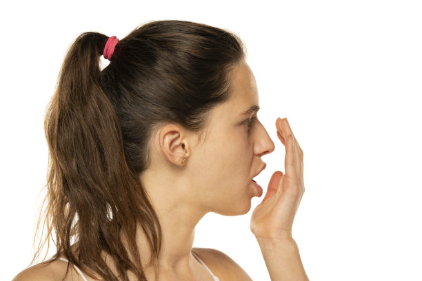 一名年轻女子在白色背景上用手掌检查她的呼吸图片下载