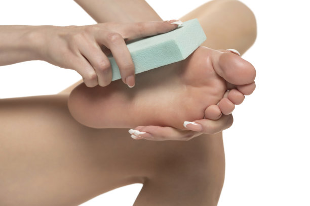 一个女人用浮石在白色的工作室背景上锉她的脚图片下载