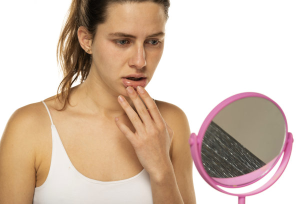 镜子前忧心忡忡的年轻女子在白底上摸了摸她的嘴图片下载