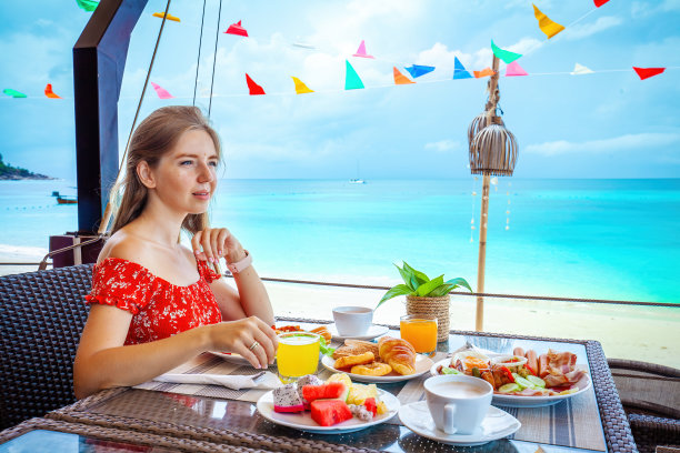 女人在你的暑假享受海边早餐。图片下载