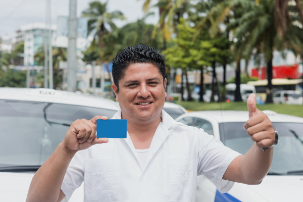 拉丁美洲墨西哥城市街道上的拉丁裔出租车司机男子手持空白卡，背景是汽车，西班牙裔成年人图片下载