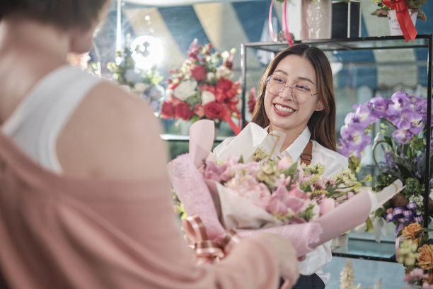 女花匠在花店给顾客送鲜花。图片下载