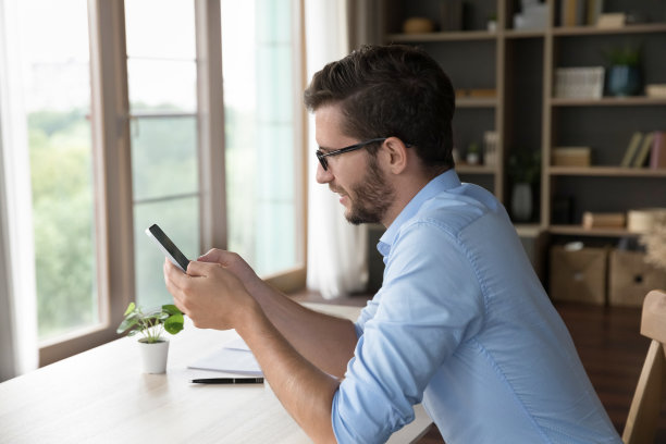 专注的年轻自由商人使用智能手机进行工作沟通图片下载
