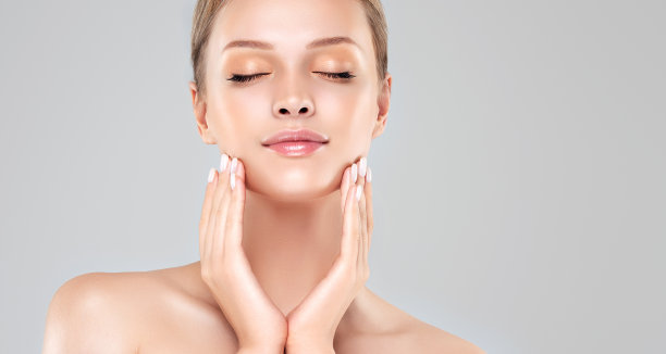 漂亮的年轻女子化着精致的妆，抚摸着她的脸。完美的脸上挂着淡淡的微笑。美容。图片下载