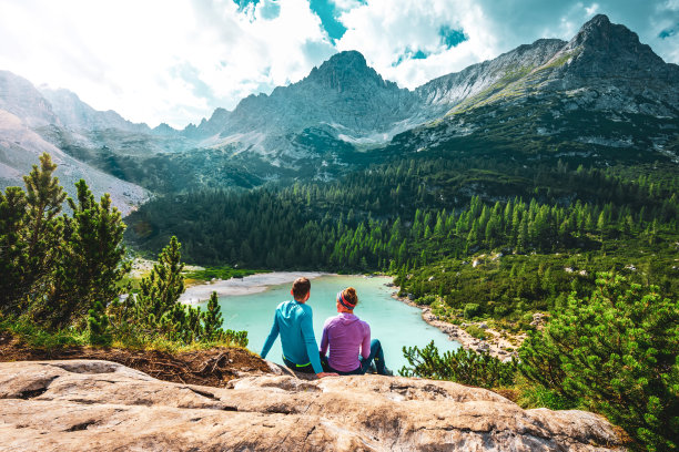 一对年轻的运动夫妇在一个美丽的休息点欣赏蓝绿色的索拉皮斯湖。索拉皮斯湖，白云石，贝卢诺，意大利，欧洲。图片下载