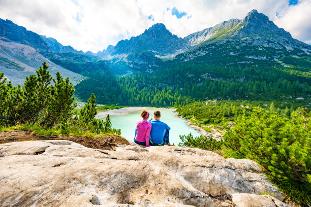 一对年轻的运动夫妇在一个美丽的休息点欣赏蓝绿色的索拉皮斯湖。索拉皮斯湖，白云石，贝卢诺，意大利，欧洲。图片下载