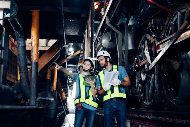 铁路工程师队伍穿着安全制服和安全帽，在列车，车轮和控制系统下进行安全旅行乘客的检查。横幅封面设计。图片下载