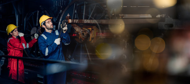 铁路工程师队伍穿着安全制服和安全帽，在列车，车轮和控制系统下进行安全旅行乘客的检查。横幅封面设计。图片下载