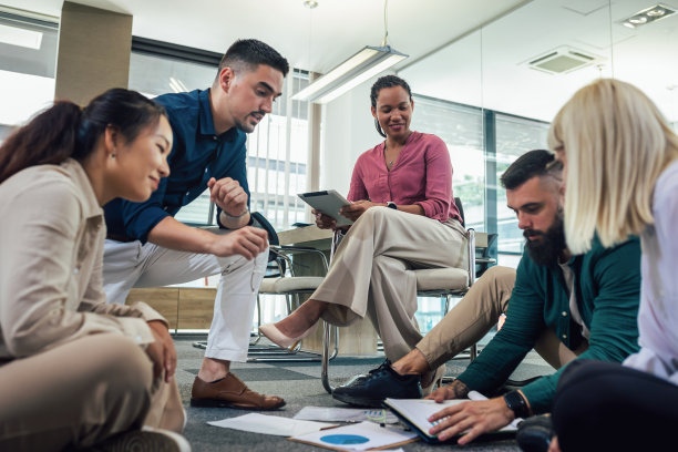 一群专业人士坐在办公室的地板上一起工作图片下载