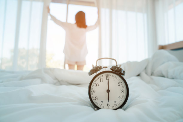 年轻的女人早上在家，专注于闹钟，闹钟叫醒了房间里的女人图片下载