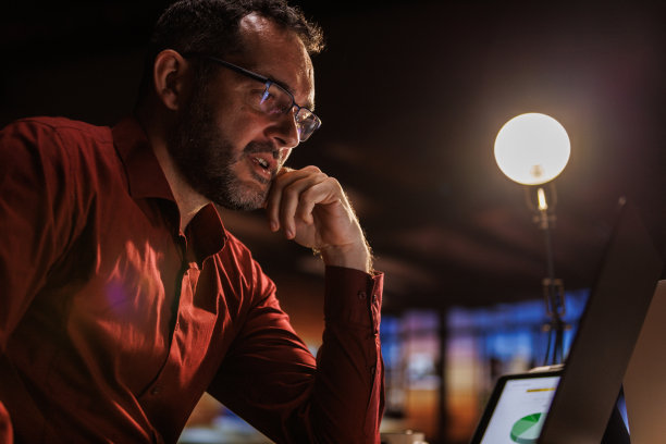 勤奋的商人戴着眼镜，在办公桌前使用笔记本电脑工作到很晚图片下载