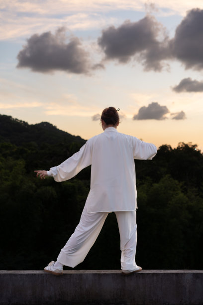 一位亚洲妇女正在公园里练习健身运动太极拳。图片下载