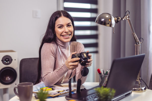女摄影师在工作场所使用笔记本电脑，在工作室使用电脑图片下载