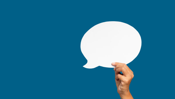 一个语音泡泡的概念。在蓝色背景下，手握着一个空的白色演讲泡泡。图片下载