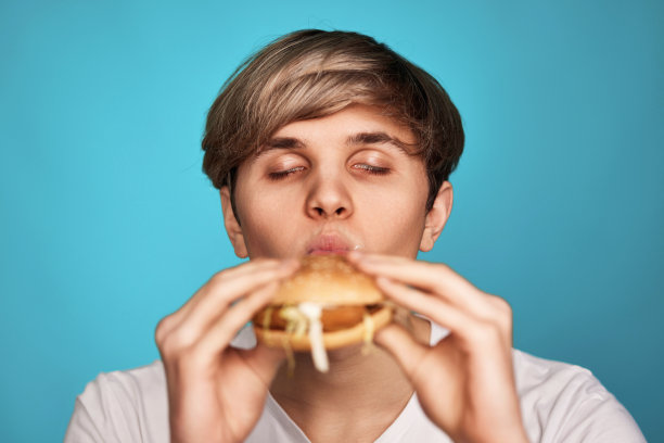 非常饥饿的年轻人拿着美味的汉堡图片下载