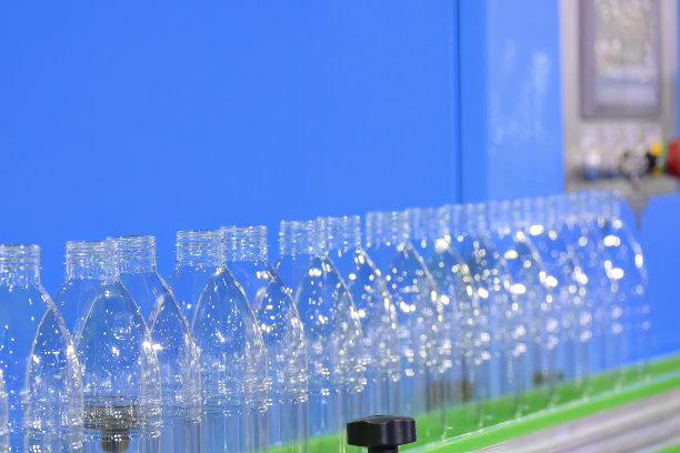 将空的饮水瓶放在传送带上进行灌装过程。图片下载