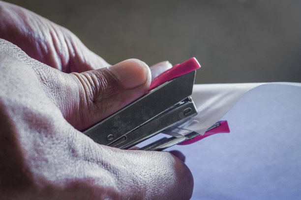 一个用订书机在订书机订文件的手画。图片下载