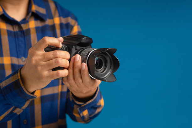 站在蓝色背景上手持数码相机的特写图片下载